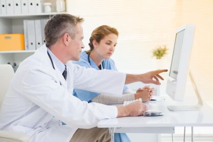 Ein Arzt und eine medizinische Fachangestellte interpretieren einen Befund auf einem Computer